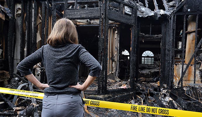 A person is inspecting a fire damaged house A person is inspecting a fire damaged house