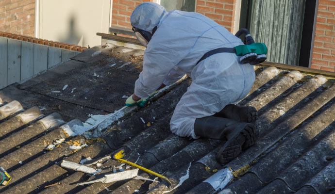 Person cleaning asbestos waste on a rooftop