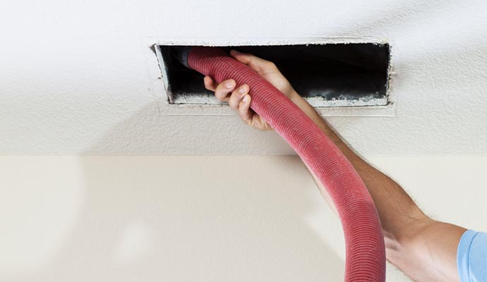 Person cleaning duct with equipment