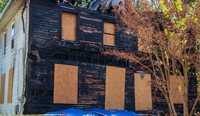 A fire damaged house with boarded-up windows