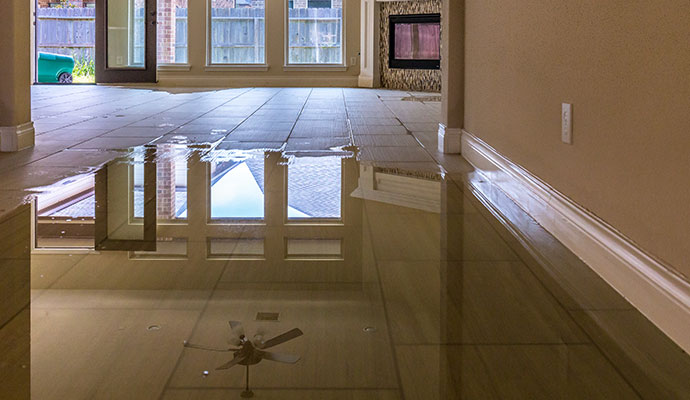 A living room with a tiled floor partially flooded with water