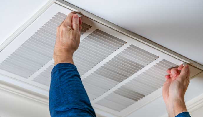 Person replacing an air filter in a ceiling vent