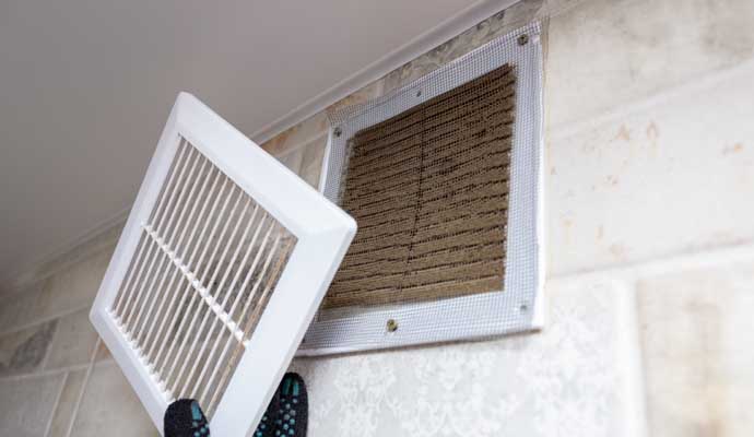 A person removing a dirty air vent filter