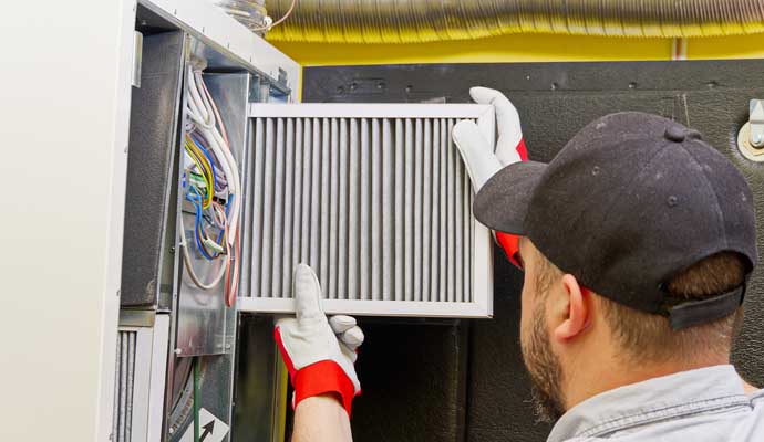 A person replacing an air filter in an HVAC system