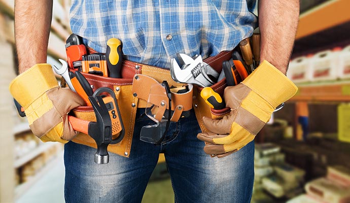 Professional handyman wearing gloves with tool belt A handyman wearing gloves and a tool belt filled with various tools