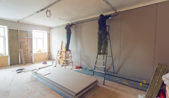 Person installing drywall in a room