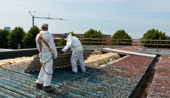 Professional workers restoring asbestos damaged roof Professional workers restoring asbestos damaged roof