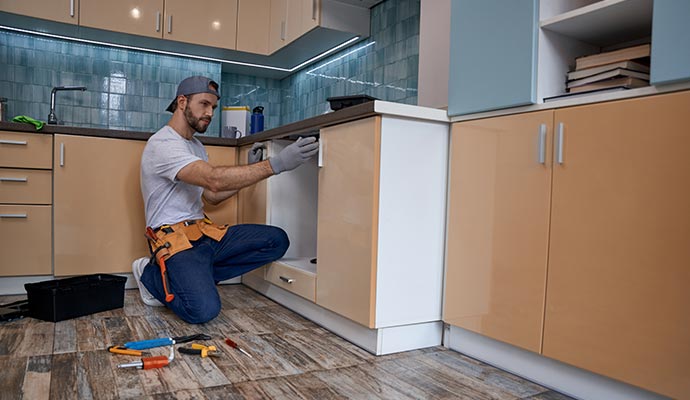 A handyman is fixing a cabinet A handyman is fixing a cabinet