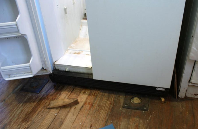 Close-up view of damaged wooden floor due to refrigerator water leak