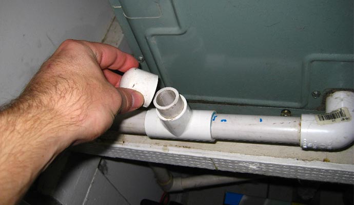 Person inspecting a/c drain unit