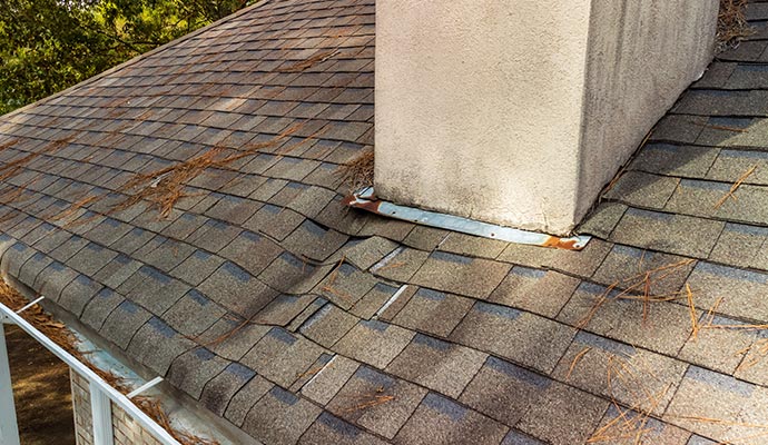 Roof with damaged shingles and chimney