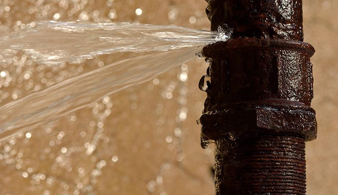 A rusty pipe with water leaking out from a crack