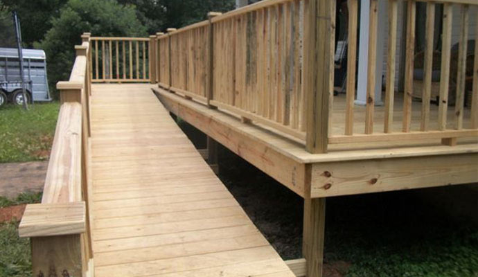 A wooden ramp leading up to a deck with wooden railings